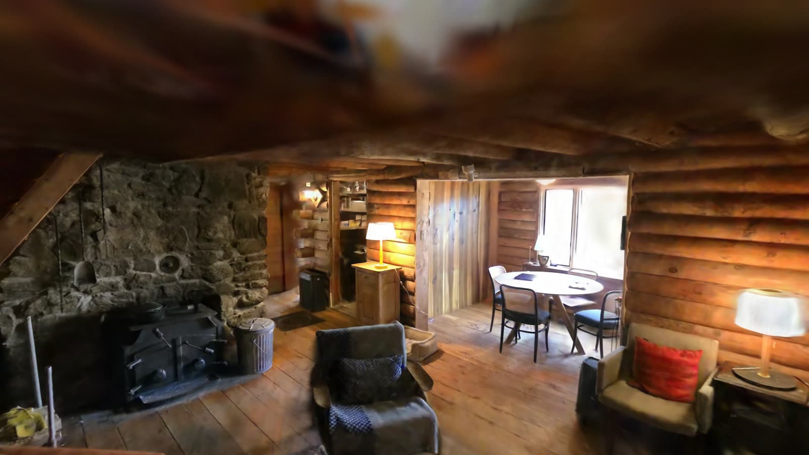 The living room, with the stone fireplace and the dining table beyond