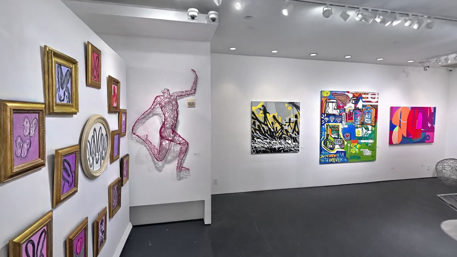 A salon-style wall and a wire figure
